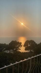 a misty sunrise over a body of water with trees at La GEMMA di Orrico in Anacapri