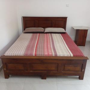 a bed with a wooden frame with a striped mattress at Villa in Yakkala, Gampaha 