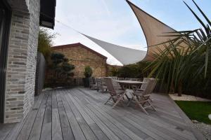 a patio with a table and chairs on a wooden deck at Villa au Gré du Vent in Bray-Dunes