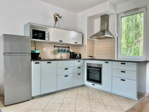 a white kitchen with white cabinets and a window at Feel Home DeLuxe CORVIN # FREE PARKING # AC # Elevator in Budapest