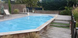 una gran piscina con terraza de madera en Bienvenue Chez Vous en Émancé