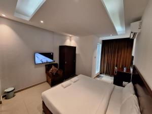ALJAWHARA INN HOTEL في سيب: غرفة نوم مع سرير وتلفزيون على الحائط