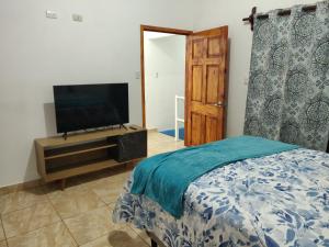 a bedroom with a bed and a flat screen tv at Casa Comotini in Tamanique