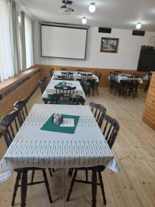 Horský hotel Sport في كورينوف: غرفة مع طاولات وكراسي وشاشة عرض