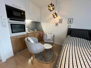 um pequeno quarto com uma cama, uma televisão e uma cadeira em Apartment UNA Sarajevo em Sarajevo