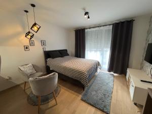 um quarto com uma cama, uma cadeira e uma janela em Apartment UNA Sarajevo em Sarajevo