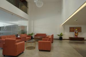- un espace d'attente avec des chaises et des tables orange dans un bâtiment dans l'établissement Gokulam Park Guruvayur, à Guruvāyūr