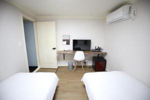 Habitación con 2 camas y escritorio con ordenador. en Hotel Golden Hill en Seúl