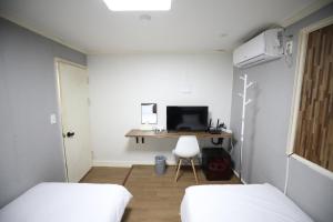 Habitación con 2 camas y escritorio con ordenador. en Hotel Golden Hill en Seúl
