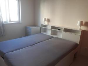 een witte slaapkamer met een bed en een raam bij Apartment Finn in Rovinj