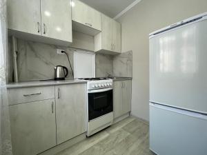 a kitchen with a stove and a refrigerator at 2-комнатная квартира в центре города, Интернациональная 94 in Petropavlovsk