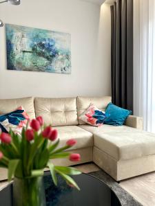 ein Wohnzimmer mit einem Sofa und einem Tisch mit Blumen in der Unterkunft White Apartament Częstochowa Centrum 2-bedroom in Częstochowa
