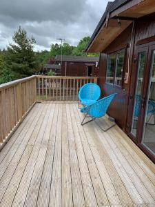 a deck with two blue chairs on a house at 2 bedroom lodge - The Cherries (24) Caer beris holiday park in Builth Wells