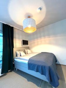 a bedroom with a blue bed and a chandelier at New 2BR design home with sauna Espoo Park in Espoo