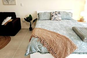 1 dormitorio con cama con manta y sofá en WhitsunStays - Le Beach Shack, en Mackay