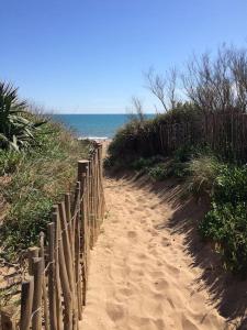 une clôture en bois sur un chemin de sable menant à la plage dans l'établissement RESSOURCEZ VOUS AU SOLEIL, à Sérignan