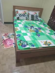 a bed with a green and white comforter and pillows at Kapowlito Real Estate Casa Grootblijdenshoopweg in Paramaribo