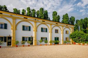 a large white building with trees in the background at Agriturismo Il Leone della Torre in Contrada Ronchiel