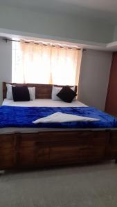 a bedroom with a bed with a blue comforter and a window at Chill@hill in Ooty