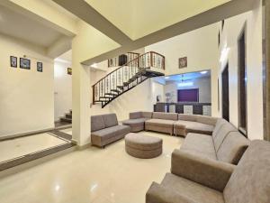 a large living room with couches and a staircase at Seven Villa with Swimming pool in Panchgani