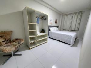 ein weißes Schlafzimmer mit einem Bett und einem Stuhl in der Unterkunft Residencial Atalaia Sul in Aracaju