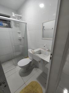 La salle de bains blanche est pourvue de toilettes et d'un lavabo. dans l'établissement Residencial Atalaia Sul, à Aracaju