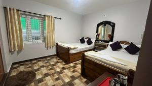 a bedroom with two beds and a mirror and a window at Chill@hill in Ooty