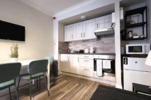 uma cozinha com armários brancos e uma mesa e cadeiras em Cosy 1bed apartment with nice patio and fast WIFI F1 em Dublin