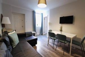 uma sala de estar com um sofá e uma mesa com cadeiras em Cosy 1bed apartment with nice patio and fast WIFI F1 em Dublin