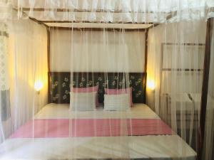1 dormitorio con cama con dosel y cortinas blancas en Sumudu Modern Villa, en Tangalle