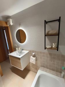 un bagno con un lavandino, una vasca e uno specchio di Apartamento a estrenar en A Pobra do Caramiñal a A Pobra do Caramiñal Altre 17 foto