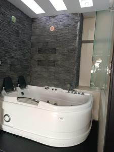 baño con bañera blanca y pared de ladrillo en Hotel Quezada Hermanos, en Santo Domingo de los Colorados