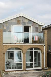 a brick house with large windows and a balcony at Ty Traeth Beach House in Tywyn