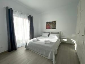 a white bedroom with a large bed and a window at Casa Antonio - apartamento Sol in Playa de San Juan