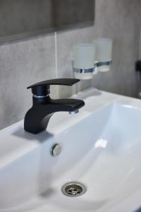 a bathroom sink with a black faucet and two glasses at Karakol Resort in Karakol