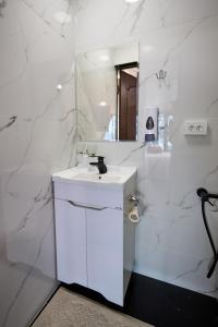a white bathroom with a sink and a mirror at Karakol Resort in Karakol