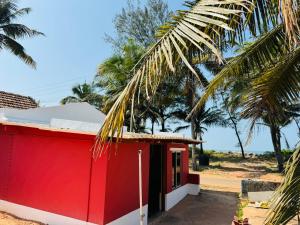 um edifício vermelho com palmeiras ao fundo em Payal Nivas beach cottage em Padubidri