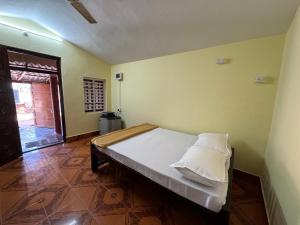 um quarto com uma cama com lençóis e travesseiros brancos em Payal Nivas beach cottage em Padubidri