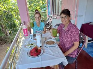 Luxman Guest House في بولوناروا: يجلس شخصان على طاولة مع طبق من الفاكهة