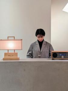 a woman standing in front of a desk with a computer at MUKUten舎富士宮 MUKUtensha Fujinomiya natural wood retreat hotel in Fujinomiya