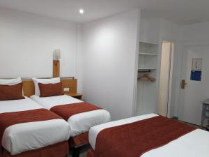 a hotel room with two beds with red sheets at Hotel Morand in Rouen