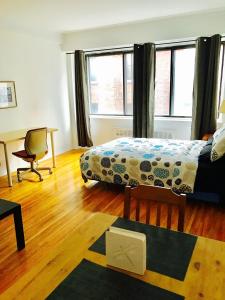 a bedroom with a bed and a desk and two windows at Stylish Montreal Apartment: Comfortable Stay in the Golden Square Mile in Montreal