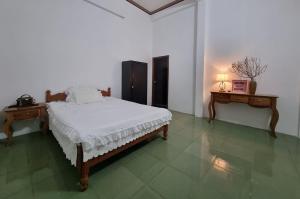 a white bedroom with a bed and two tables at Katie's homestay in Ðông Mỹ (2)