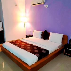 a bedroom with a large bed with a purple wall at SPIRIT OF INDIA in Lagos