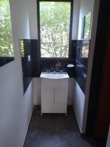 baño con lavabo blanco y ventana en Bosquecito de Carpin en Carpintería