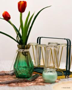 een vaas met een rode bloem erin naast andere glazen bij Relax Spot View @ Meru Raya in Ipoh