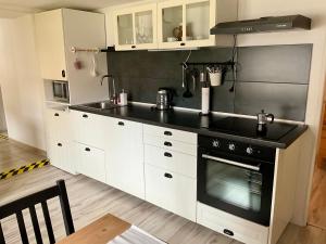 a kitchen with white cabinets and a black stove top oven at Vidiecky domček in Pohronská Polhora