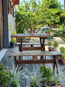 a wooden picnic table and benches in a garden at Hostel das fadas in Paraty