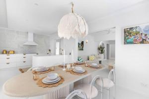 a white dining room with a table and a chandelier at WhitsunStays - The Cyclades in Mackay