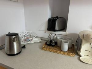 a kitchen counter with a coffee maker and cups and a toaster at IaZi Apartament in Braşov